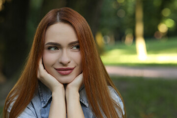Obraz premium Portrait of beautiful young woman with red hair outdoors. Space for text. Attractive lady posing for camera