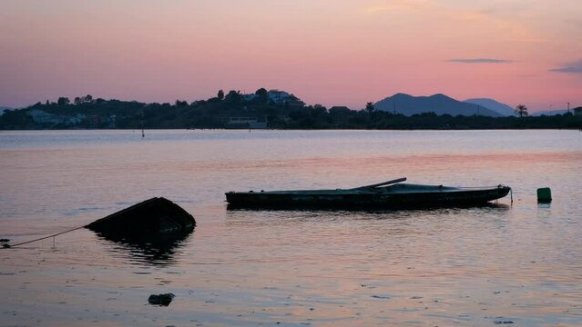 Surfing boat silhouette in nightfall sea. A view of surfing boat silhouette abandoned on the water surface during colorful nightfall in summer.