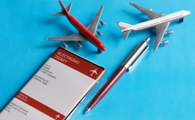 An electronic air ticket form on the screen of a mobile phone next to toy passenger airplanes and a...