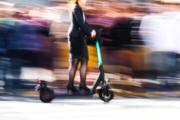 Woman rides past a crowd on an e-scooter