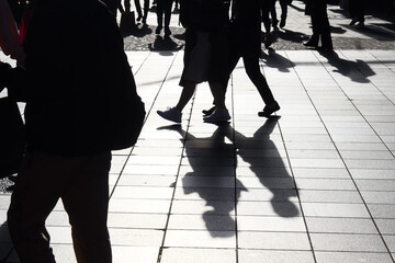 Backlit silhouettes of pedestrians walking in a pedestrian zone