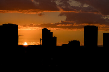 Red, Orange, and Gray Sunset Above a Dark Cityscape.