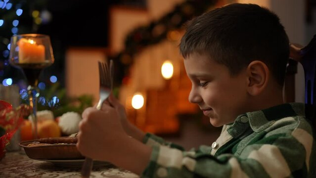 A boy sitting at a table decorated for Christmas tries to observe the Christmas ritual