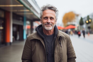 Portrait of a handsome middle-aged man with grey hair and beard on the street.