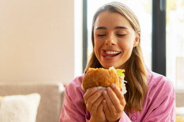 Hungry beautiful woman eating tasty  American burger sitting in cafe - obrazy, fototapety, plakaty