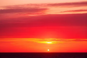Gordijnen 真っ赤に染まる夕焼け太陽が沈む瞬間の海の景色 © sky studio