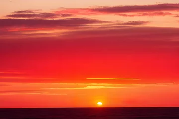 Fotobehang 真っ赤に染まる夕焼け太陽が沈む瞬間の海の景色 © sky studio