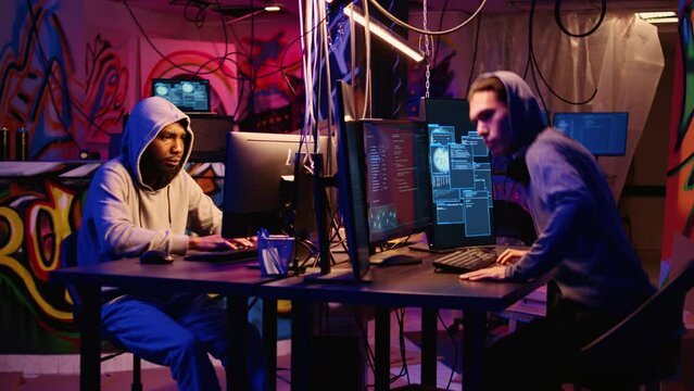 Hackers in secret base talking about technical knowhow details before using bugs and exploits to break into computer systems and access valuable data, bypassing firewalls, zoom out shot