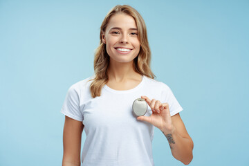 Portrait of attractive woman in white t shirt holding pacemaker in hand, looking at camera isolated...