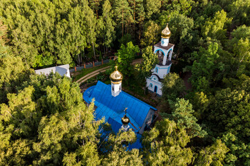 Aerial view of an orthodox church with golden crosses and domes in a forest area, a church in a...