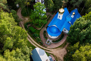 Aerial view of an orthodox church with golden crosses and domes in a forest area, a church in a...