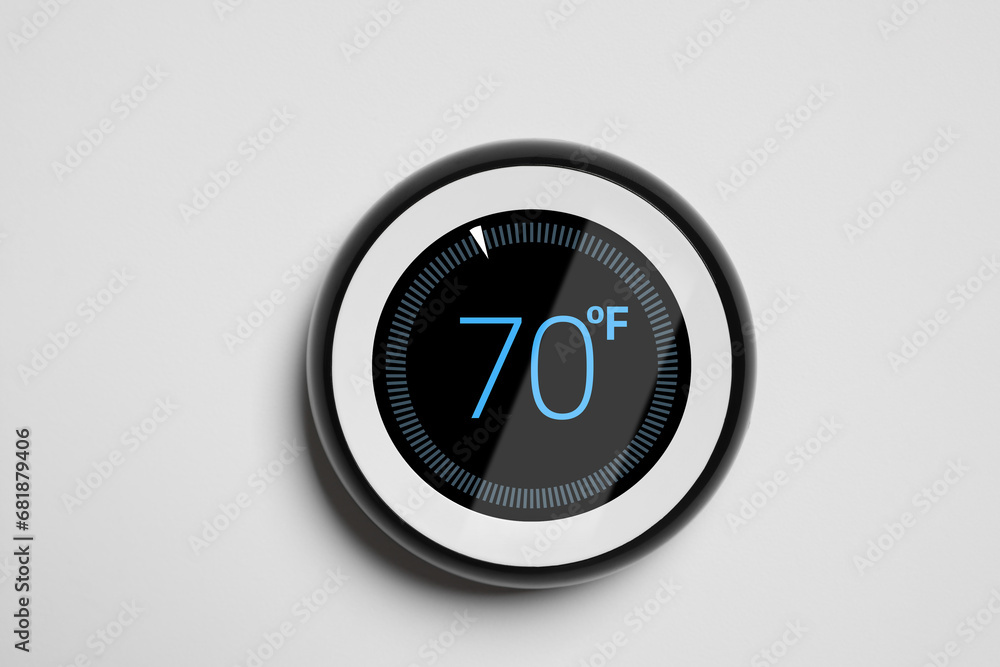 Poster thermostat displaying temperature in fahrenheit scale. smart home device on white wall