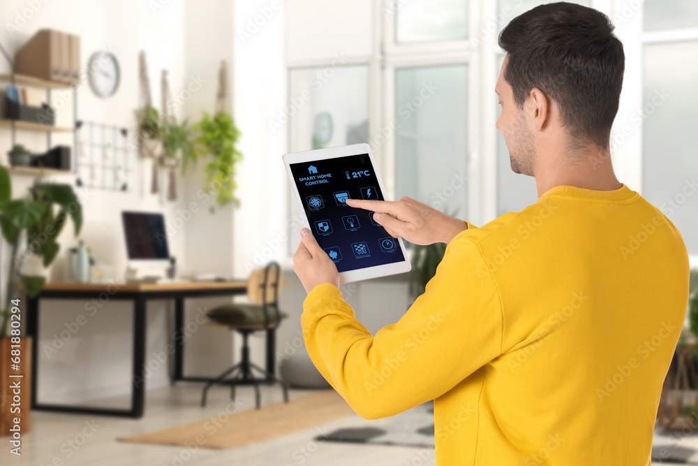 Fototapete man using smart home control system via application on tablet indoors