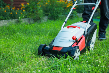 Man cutting grass with lawn mower in garden, closeup. Space for text