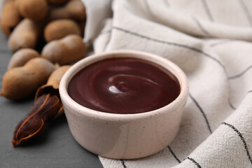 Bowl of tamarind sauce and fresh pods on table, closeup