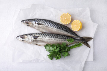 Tasty salted mackerels, parsley and cut lemons on light table, top view