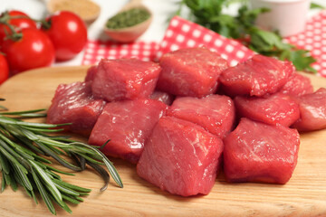 Cooking delicious goulash. Raw beef meat and rosemary on wooden board, closeup