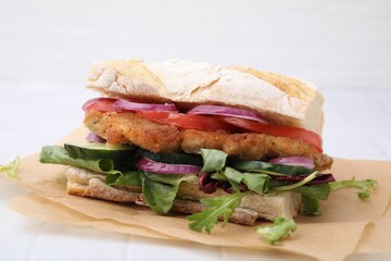 Delicious sandwich with schnitzel on white tiled table, closeup