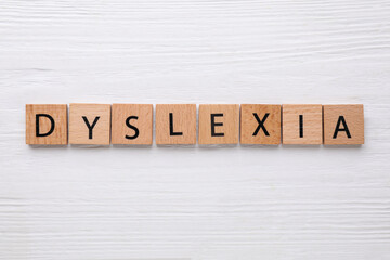 Tiles with word Dyslexia on white wooden table, flat lay