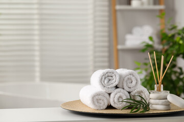 Spa composition. Towels, reed diffuser, stones and palm leaves on white table in bathroom, space...