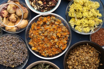 Many different dry herbs and flowers on blue table, flat lay