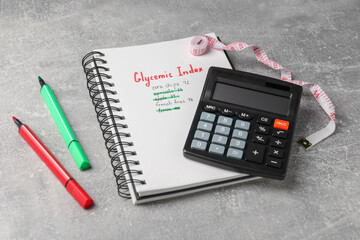 Glycemic Index. Notebook with information, markers, calculator and measuring tape on light grey...