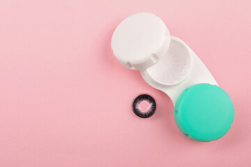 Case with color contact lenses on pink background, top view. Space for text