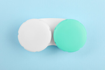 Case with color contact lenses on light blue background, top view