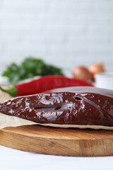 Piece of raw beef liver on white wooden table, closeup. Space for text