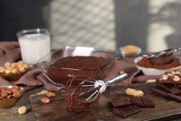 Whisk with chocolate cream and ingredients on grey table, closeup. Space for text