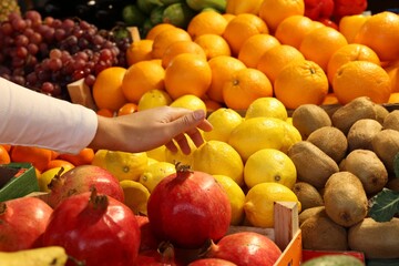 Woman picking fresh lemon at market, closeup