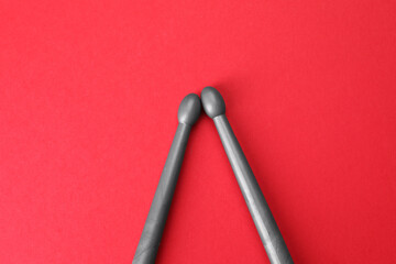 Two gray drum sticks on red background, top view