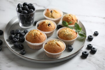 Delicious sweet muffins with blueberries and mint on white marble table