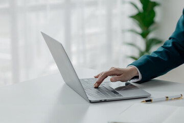 Businesswoman is sitting and working in the office, Employee is looking for information on laptop, Recording various information on paper,