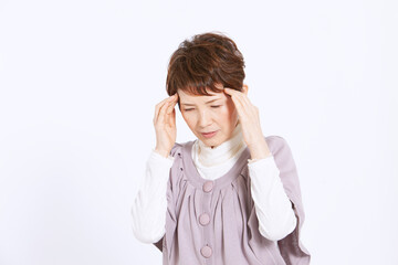 こめかみを押さえるシニア女性