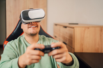 Happy young man enjoying playing console using VR goggles
