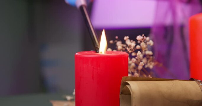 Hand with gas lighter sets fire to red candle atmosphere of romantic restaurant dinner date, dry flower Salon, spa, massage, feng shui interior for relaxation Holiday table decoration, celebration