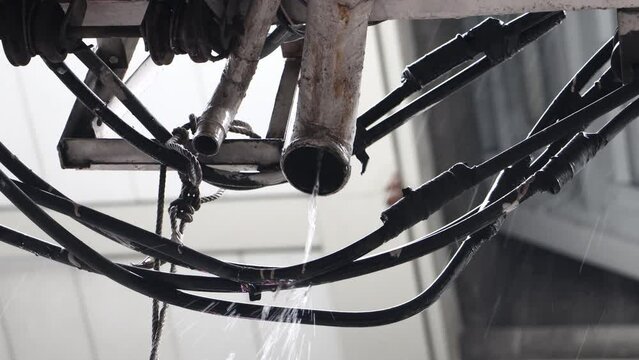 Rain water flows out of the pipe onto the electric cables installed on building on a street, Bangkok, Thailand