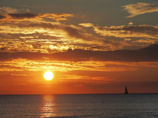 Ocean Sunset with a Sail Boat on the Horizon - 681953226