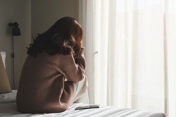 Rear view of a sad woman after reading bad news on smartphone in bedroom - obrazy, fototapety, plakaty