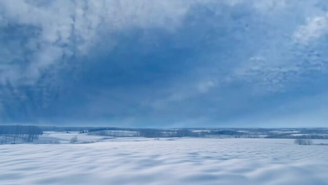 Hyperlapse of dramatic clouds in a blue sky with open winter landscape and view of fields surrounded by forests. seamless time lapse virtual 4k video animation background. Generated with AI