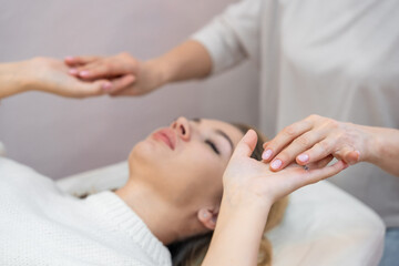 Healer launches body energy through hands before access bars therapy with young woman, stimulating positive change thoughts and emotions. Alternative medicine concept.