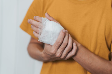 An individual wearing a yellow shirt with their left hand wrapped in a white bandage, possibly indicating an injury.