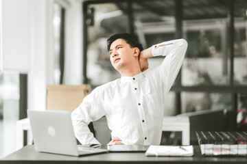 Asian middle age business man in white shirt stretching his neck, looks like he is having neck and...