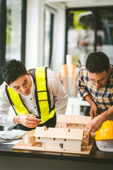 Two men engineer housing team meeting, one in safety vest holding color swatches, discussing plans,...