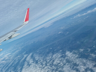 Naklejka na ściany i meble Airplane wing and sky landscape above clouds.