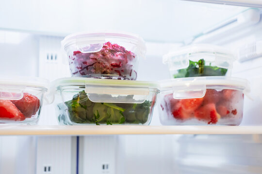 Vegetables and berries in glass boxes in the freezer close-up.