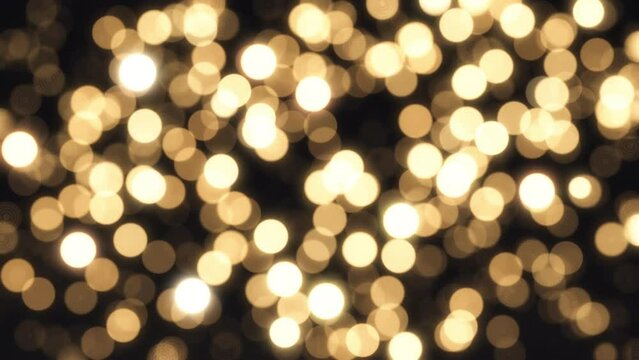 黒い背景に煌めく金色の玉ボケ / アブストラクト・クリスマス・冬のイルミネーションの背景イメージ