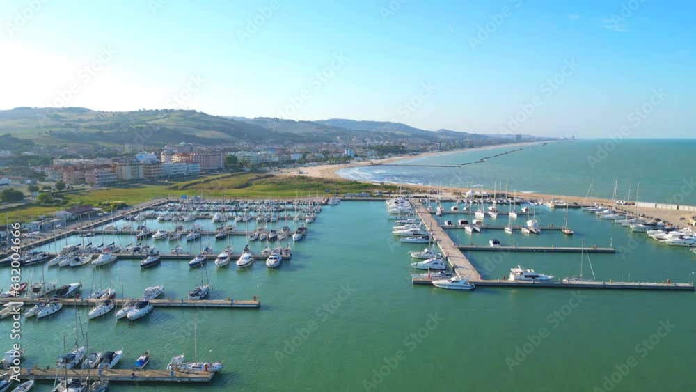 Wall mural inviting cinematic aerial push-in shot of the port of porto san giorgio, with docked boats and the w