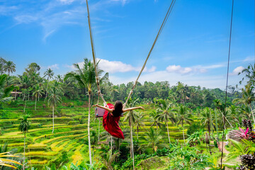 Young female tourist in red dress enjoying the Bali swing at tegalalang rice terrace in Bali, Indonesia - 682007284